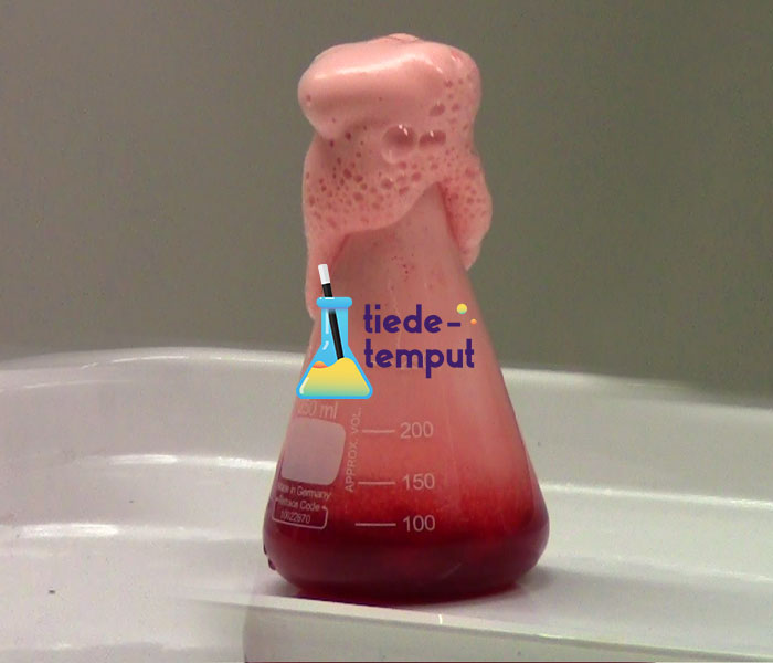 Erlenmayer pullosta pursuaa vaalean punaista vaahtoa kuin tulivuoresta laavaa. Keskellä on Tiedetemppu logo.