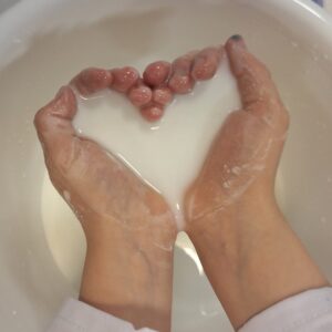 Lapsen kädet, joissa on perunajauho-vesi-seosta.